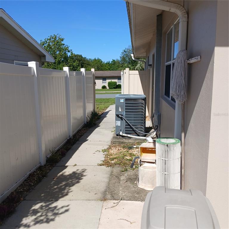 A side yard features a concrete walkway, a white vinyl fence, and an outdoor HVAC unit — 9201 N CARESSA WAY, CITRUS SPRINGS, FL