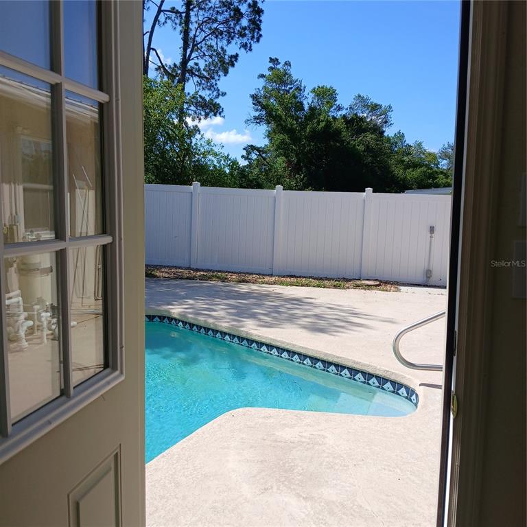 A view through an open doorway looking out onto a backyard swimming pool and fence — 9201 N CARESSA WAY, CITRUS SPRINGS, FL