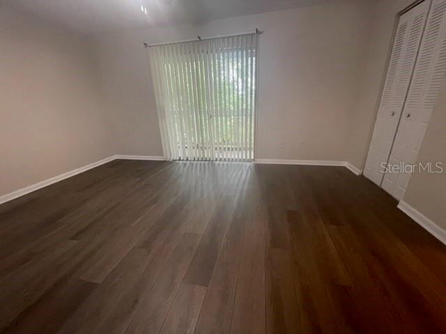 An empty room features dark wood-look flooring, light-colored walls, and a sliding glass door — 4411 SW 34TH STREET UNIT 1304, GAINESVILLE, FL