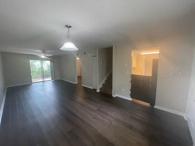 An open-concept living area features dark wood-look flooring, a pendant light, and a staircase — 4411 SW 34TH STREET UNIT 1304, GAINESVILLE, FL