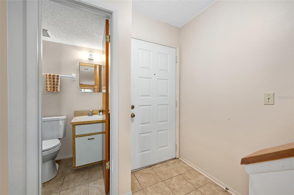 A tiled entryway features a white front door and an adjacent half bathroom — 149 WHITE FAWN DRIVE UNIT 1490, DAYTONA BEACH, FL