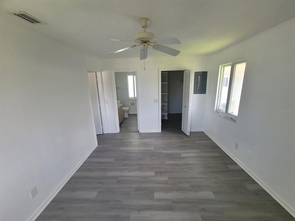 A bedroom with gray wood-look flooring, a ceiling fan, a bathroom, and a walk-in closet — 22481 WESTCHESTER BOULEVARD UNIT B35, PUNTA GORDA, FL