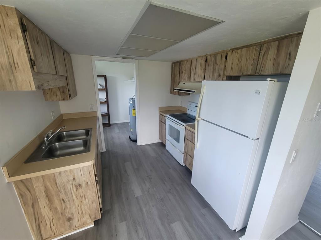 A kitchen features wood-grain cabinets, a white refrigerator, a stove, and a double-basin sink — 22481 WESTCHESTER BOULEVARD UNIT B35, PUNTA GORDA, FL