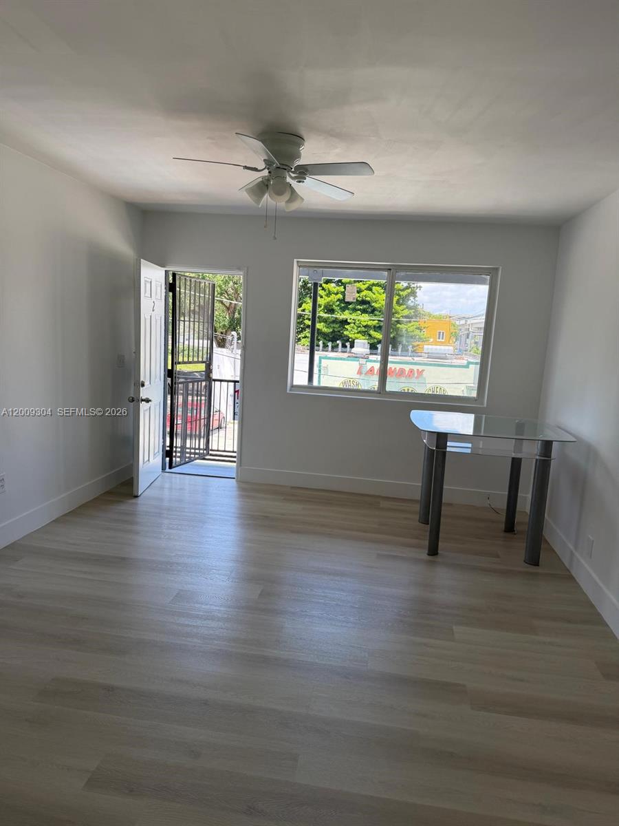 A room with light wood-look flooring, a ceiling fan, a glass table, and an open door — 4840 NW 27th Ave # 2, Miami FL 33142, MIAMI, FL