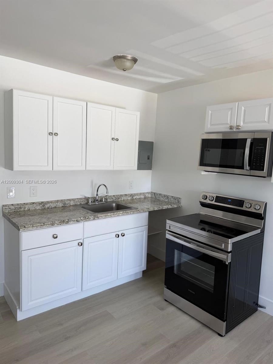 A kitchen features white cabinets, granite countertops, a stainless steel stove, and a microwave — 4840 NW 27th Ave # 2, Miami FL 33142, MIAMI, FL