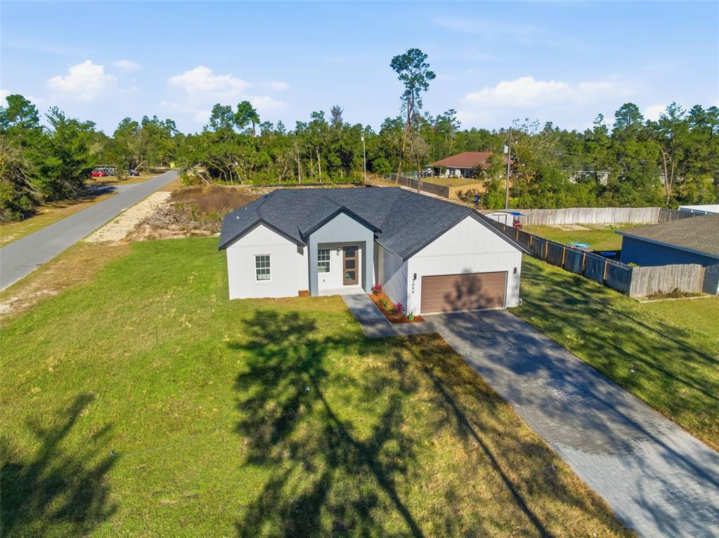 An aerial view of a modern single-story house with a dark roof and driveway — 3699 SW 169TH PLACE, OCALA, FL