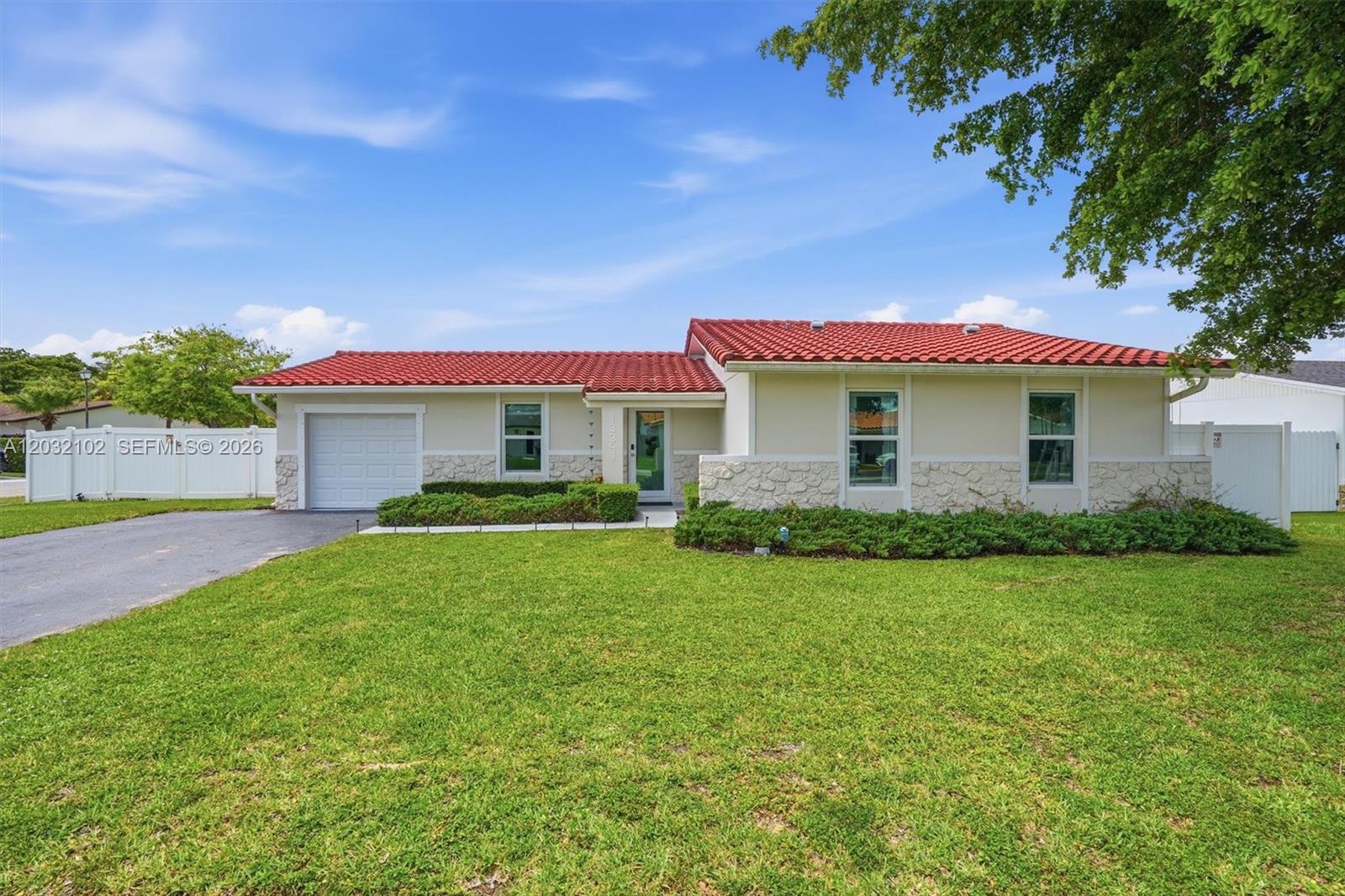 A single-story house features a red tile roof, white stone accents, and a front lawn — 13391 SW 78th St, Miami FL 33183, MIAMI, FL