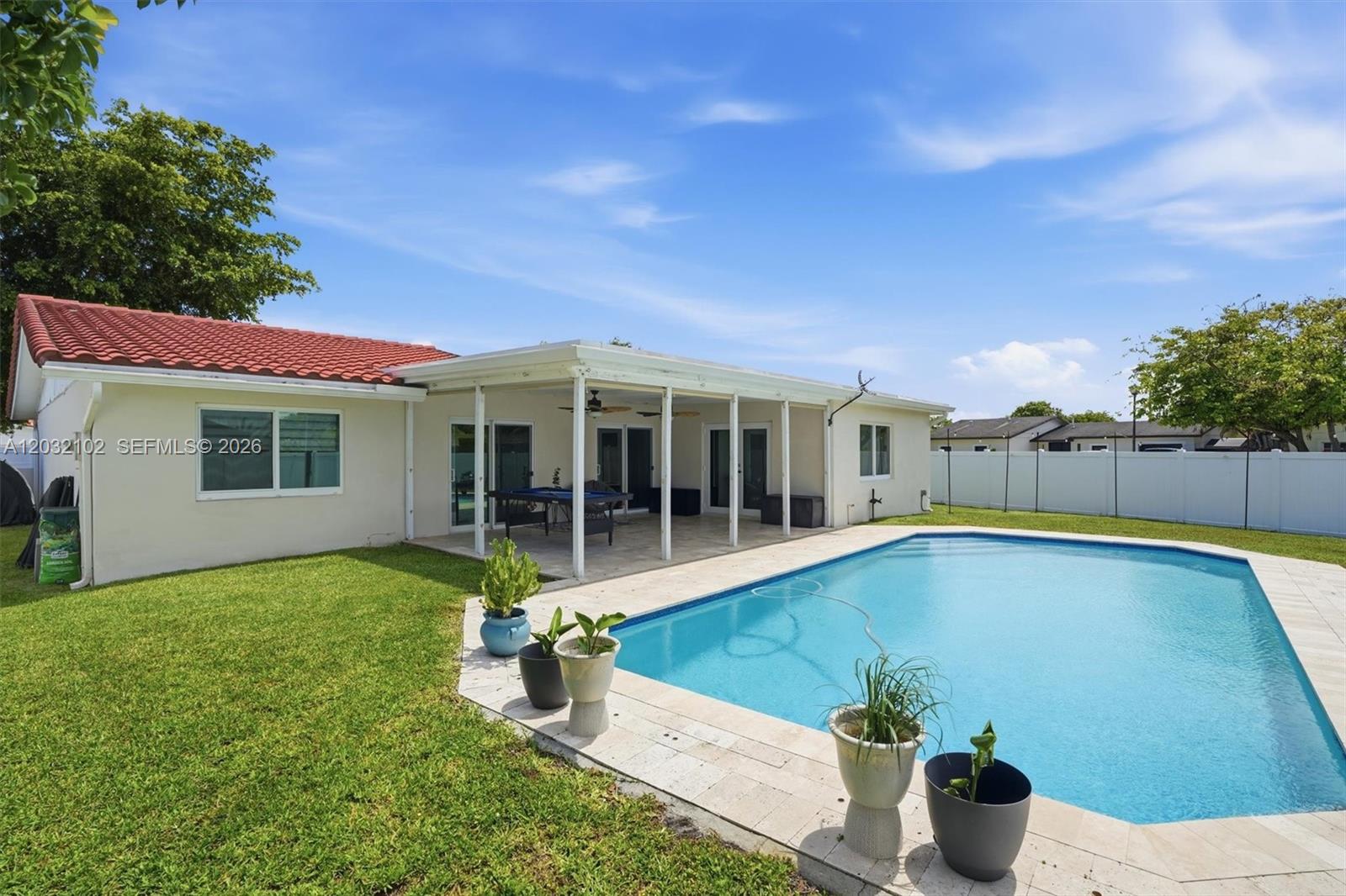 A backyard features a swimming pool, a covered patio, and a lawn under a blue sky — 13391 SW 78th St, Miami FL 33183, MIAMI, FL