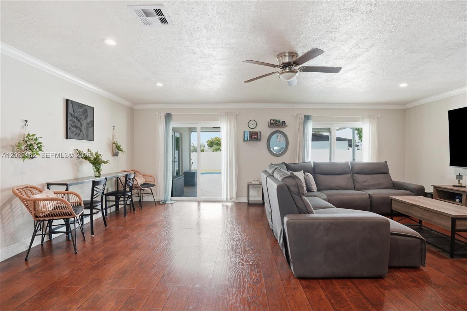 A living room features dark wood floors, a gray sectional sofa, and a dining area — 13391 SW 78th St, Miami FL 33183, MIAMI, FL