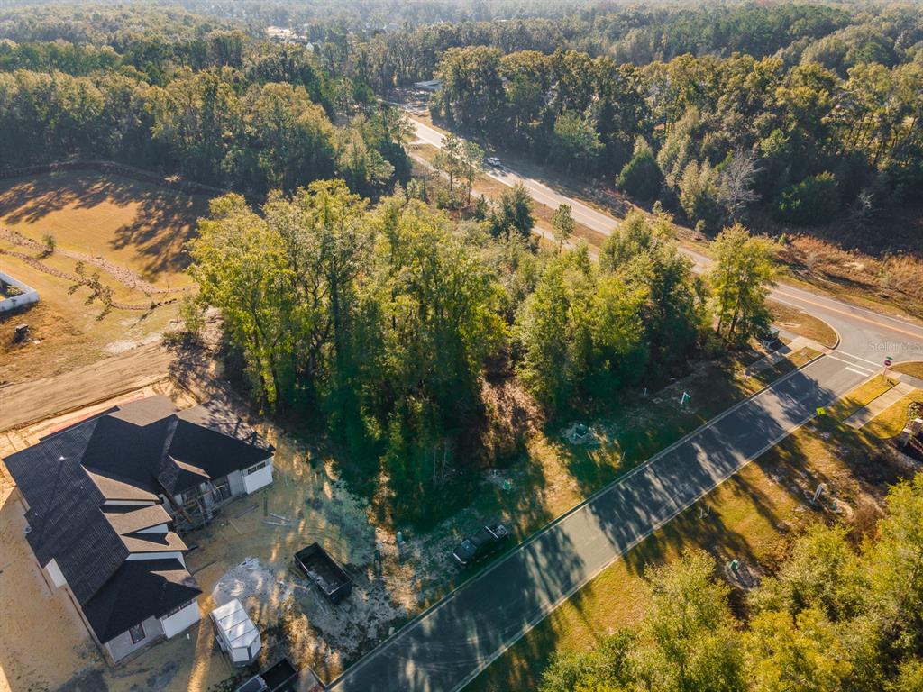 An aerial view shows a wooded residential lot next to a house under construction — 749 SW 139TH COURT, NEWBERRY, FL