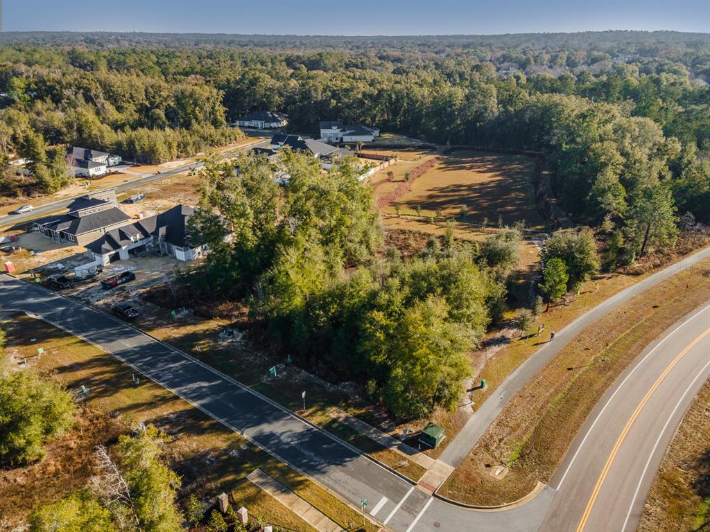 An aerial view shows a vacant residential lot surrounded by trees and nearby houses — 749 SW 139TH COURT, NEWBERRY, FL