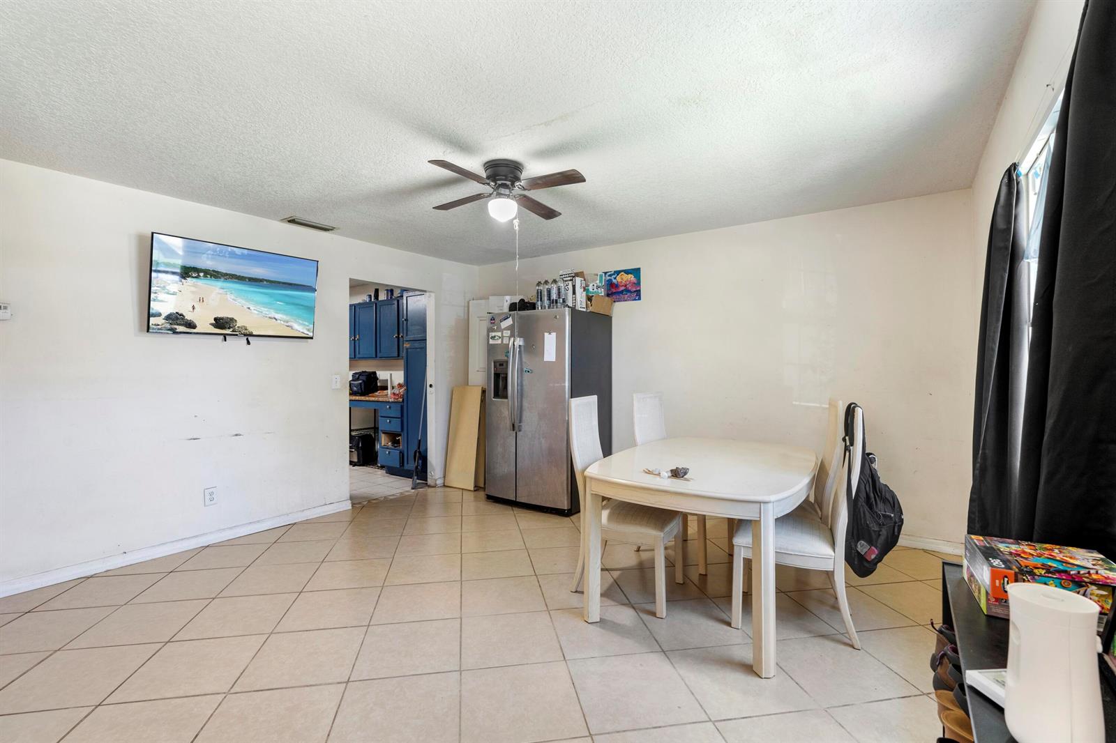 A dining area with tile flooring, a stainless steel refrigerator, and a wall-mounted television — 3136 2nd Street, Vero Beach FL 32968, VERO BEACH, FL