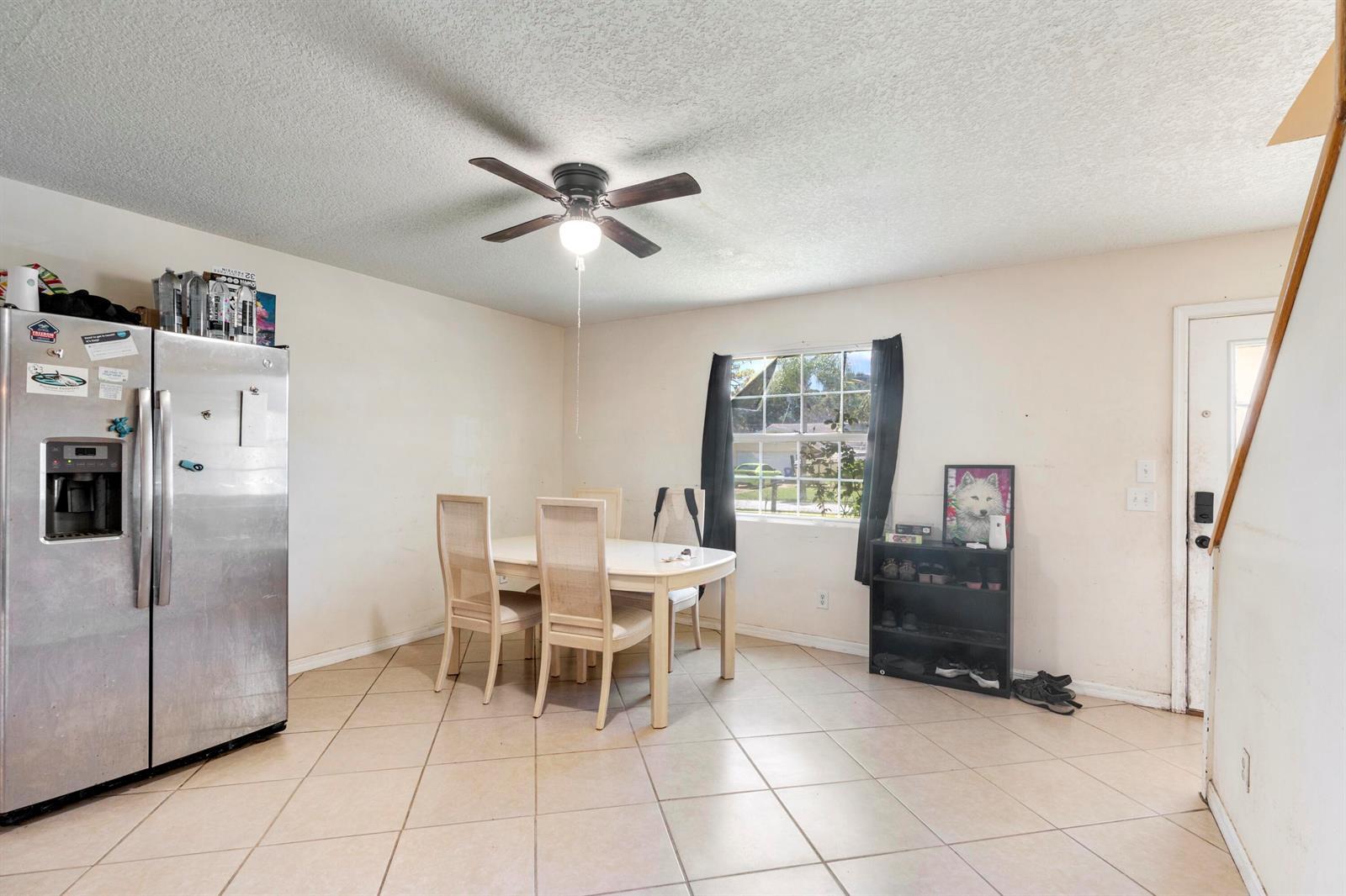 A dining area features a table with four chairs, a refrigerator, and tile flooring — 3136 2nd Street, Vero Beach FL 32968, VERO BEACH, FL