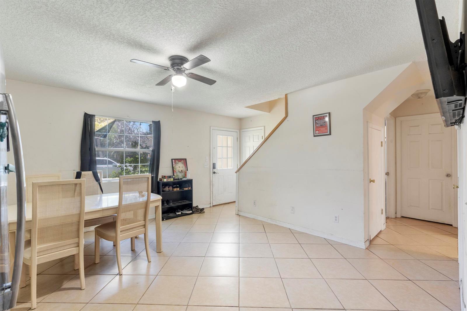 A dining area with tile floors, a ceiling fan, and a staircase leading to an upper level — 3136 2nd Street, Vero Beach FL 32968, VERO BEACH, FL