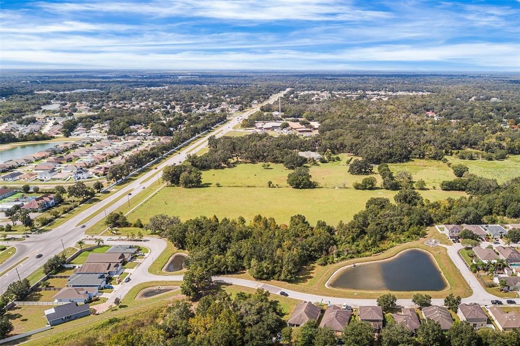 An aerial view shows a large grassy field, a heart-shaped pond, and surrounding residential neighborhoods — 2523 SHEPHERD ROAD, LAKELAND, FL