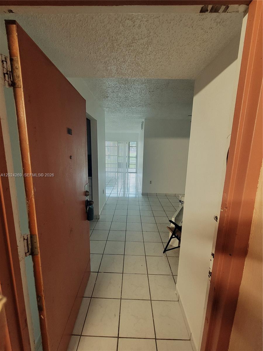 A view through an open doorway into a tiled entryway leading to a living area — 13701 Kendale Lakes Cir # 112, Miami FL 33183, MIAMI, FL