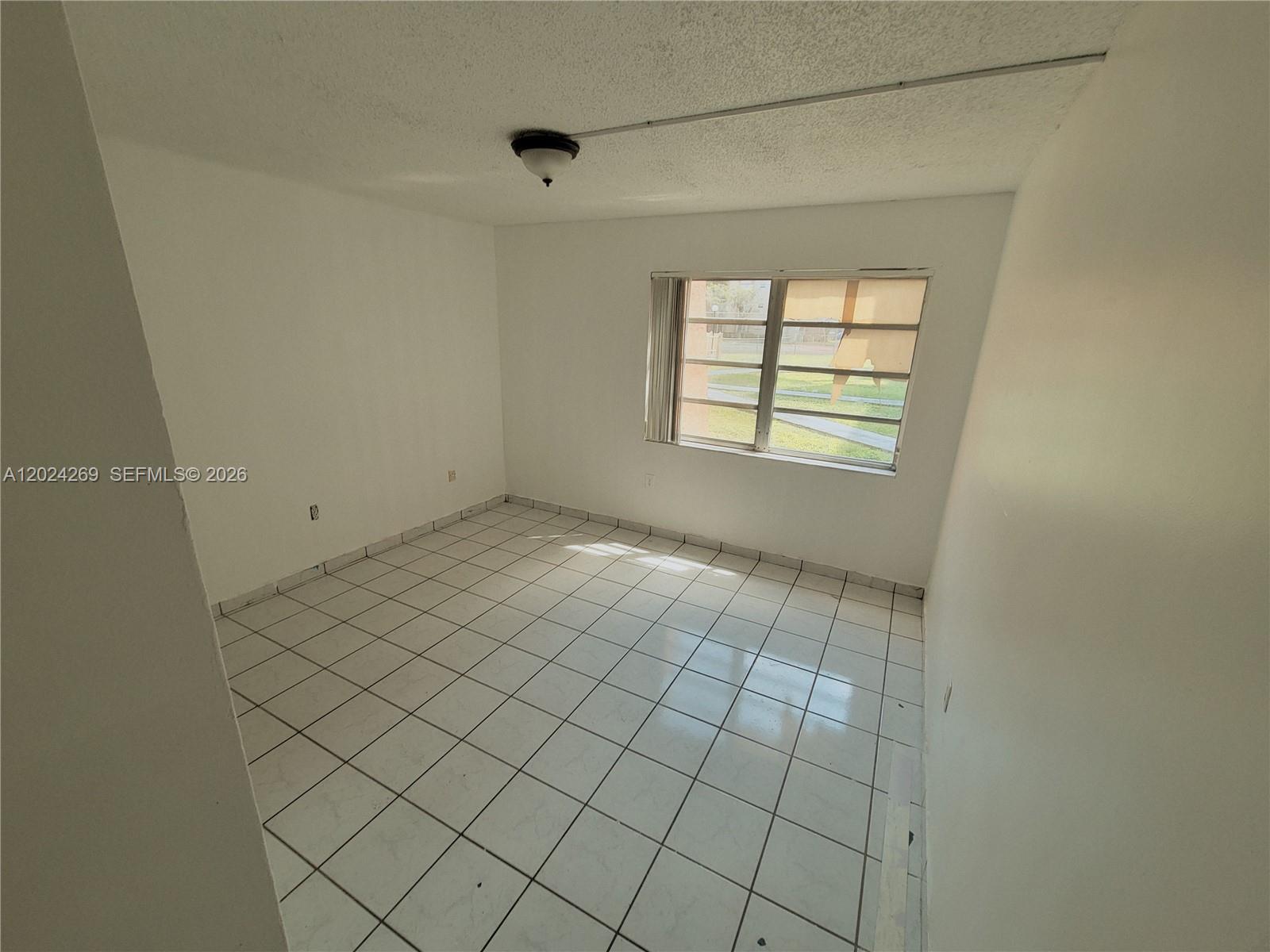 An empty room features white walls, white square floor tiles, and a single window — 13701 Kendale Lakes Cir # 112, Miami FL 33183, MIAMI, FL