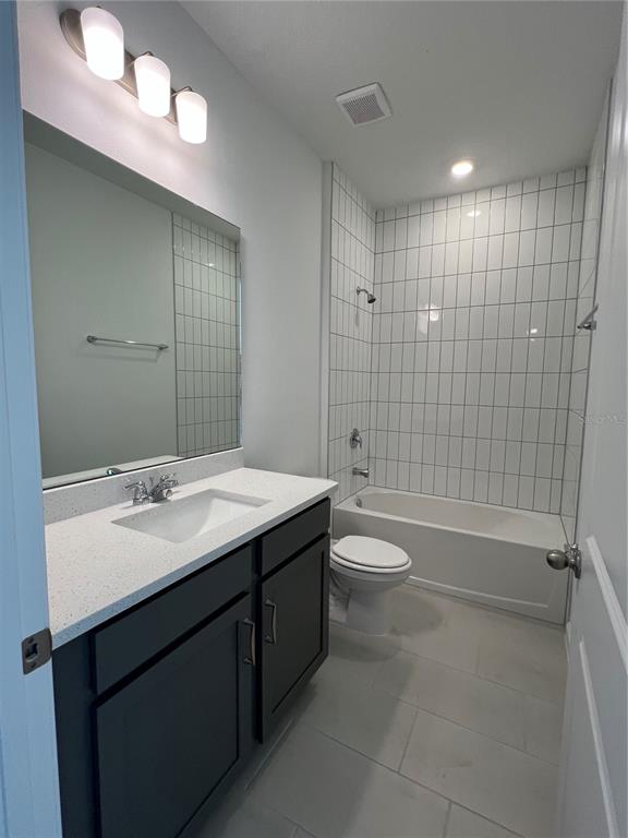 A bathroom features a dark vanity with a white countertop, a mirror, and a tiled tub — 2391 JUNIPER BERRY DRIVE, MINNEOLA, FL