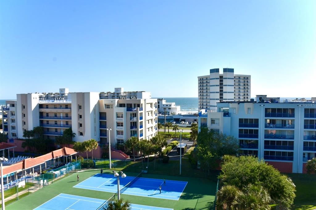 An elevated view of tennis courts in front of multi-story apartment buildings near the ocean — 5300 S ATLANTIC AVENUE UNIT 8-402, NEW SMYRNA BEACH, FL