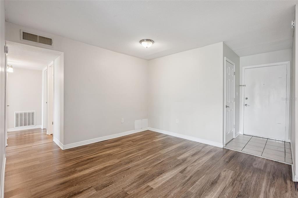 An empty room with wood-look flooring, a tiled entryway, and a white front door — 1695 LEE ROAD UNIT A116, WINTER PARK, FL