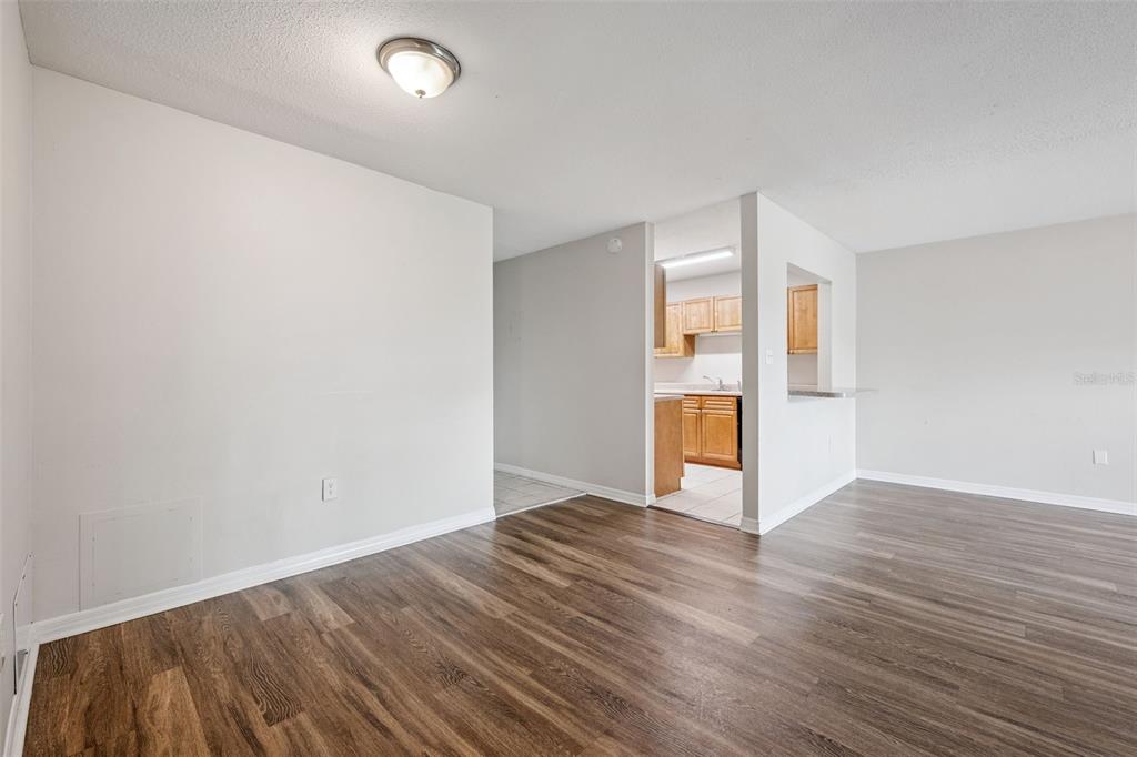 An interior view of a room with wood-look flooring and an opening to a kitchen — 1695 LEE ROAD UNIT A116, WINTER PARK, FL
