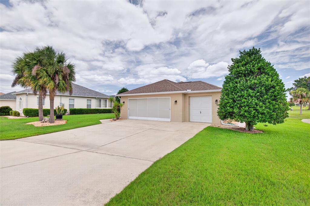 A tan house with a three-car garage and a large green lawn under a cloudy sky — 5815 NW 21ST STREET, OCALA, FL