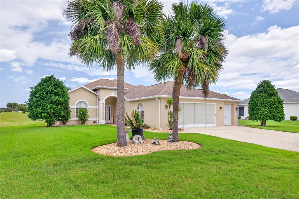 A single-story tan house with a two-car garage and two palm trees in the front yard — 5815 NW 21ST STREET, OCALA, FL