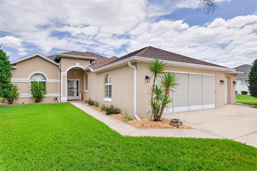 A tan stucco house with a brown shingled roof, a garage, and a front lawn — 5815 NW 21ST STREET, OCALA, FL