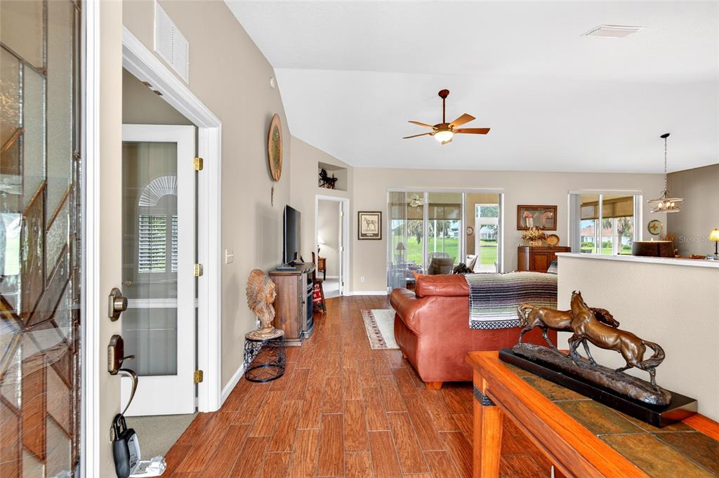 A living room with wood-look tile flooring, a leather sofa, and a horse sculpture — 5815 NW 21ST STREET, OCALA, FL