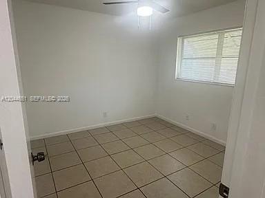 An empty bedroom features white walls, light-colored tile flooring, and a ceiling fan — 2407 Mckinley St # 2, Hollywood FL 33020, HOLLYWOOD, FL