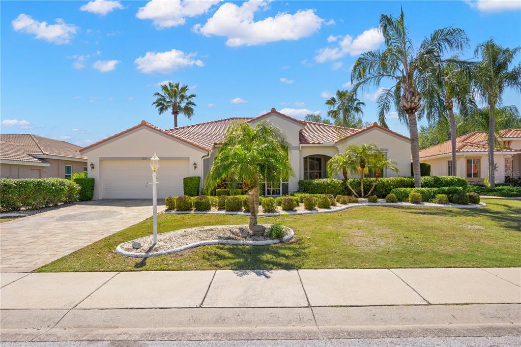 A single-story house with a tiled roof, a two-car garage, and palm trees in front — 1305 CRYSTAL GREENS DRIVE, SUN CITY CENTER, FL