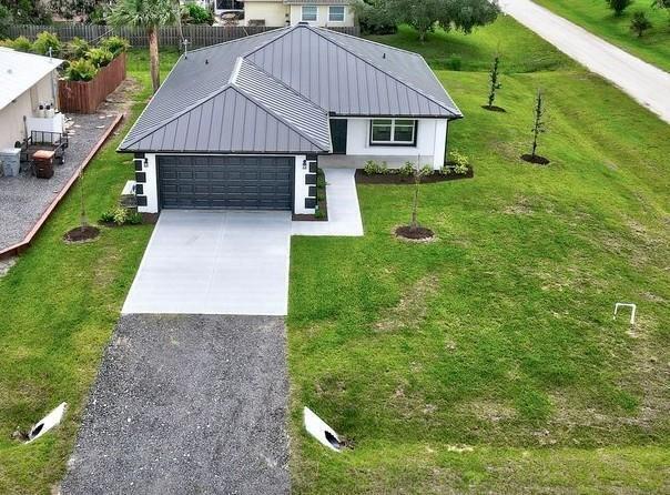 An aerial view shows a single-story house with a metal roof and a gravel driveway — VERO BEACH, FL