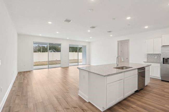 A modern kitchen with a granite island overlooks a spacious living area with sliding doors — 10 ASTERS COURT, HOMOSASSA, FL