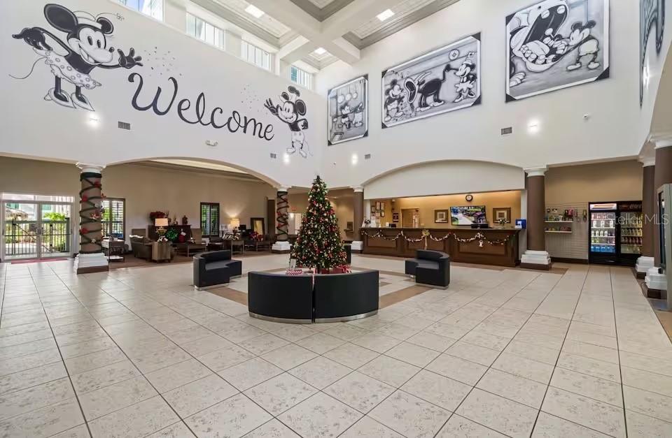 A spacious hotel lobby features high ceilings, tiled floors, a Christmas tree, and Disney-themed wall art — 8303 PALM PARKWAY UNIT 208, ORLANDO, FL