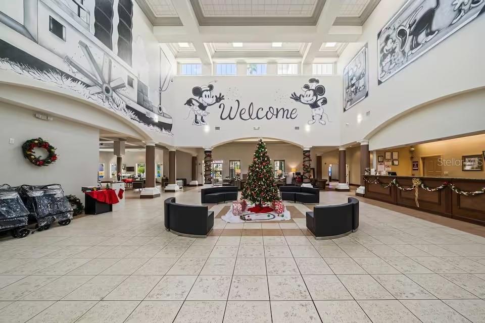 A spacious lobby features a Christmas tree, Mickey Mouse wall murals, and a reception desk — 8303 PALM PARKWAY UNIT 208, ORLANDO, FL