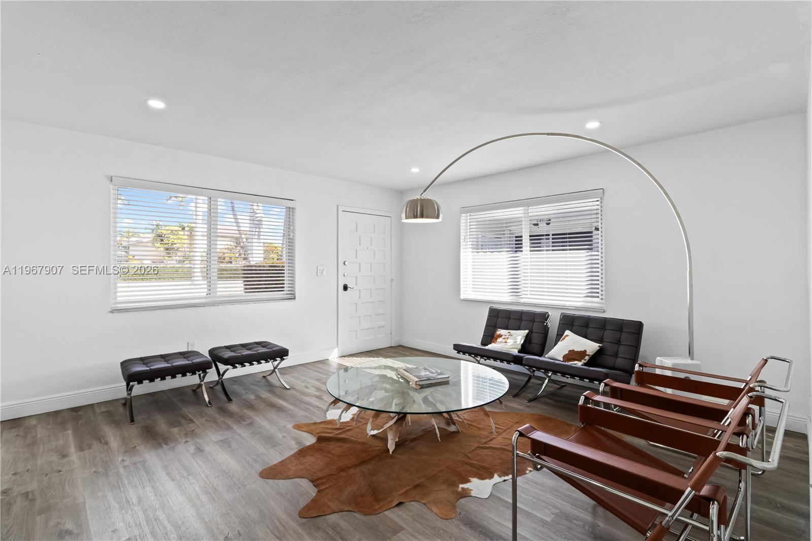 A living room features white walls, wood-look flooring, a glass coffee table, and modern seating — 10360 SW 24th St, Miami FL 33165, MIAMI, FL