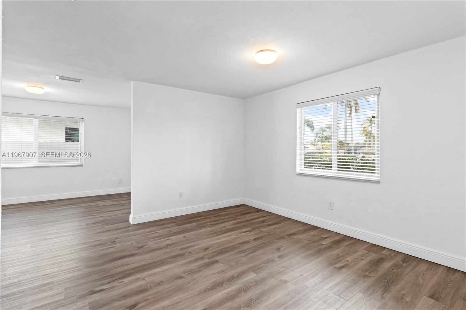An empty room with white walls, wood-look flooring, and two windows with blinds — 10360 SW 24th St, Miami FL 33165, MIAMI, FL