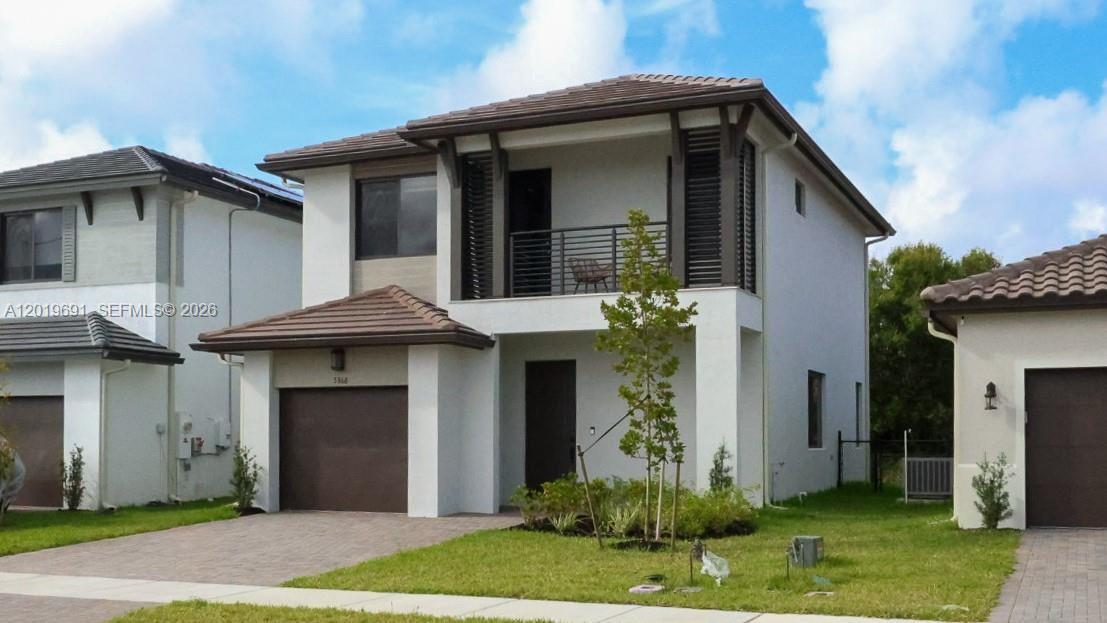 A two-story suburban house with a brown garage door, balcony, and light-colored stucco exterior — 5868 Agostino Way, Ave Maria FL 34142, AVE MARIA, FL