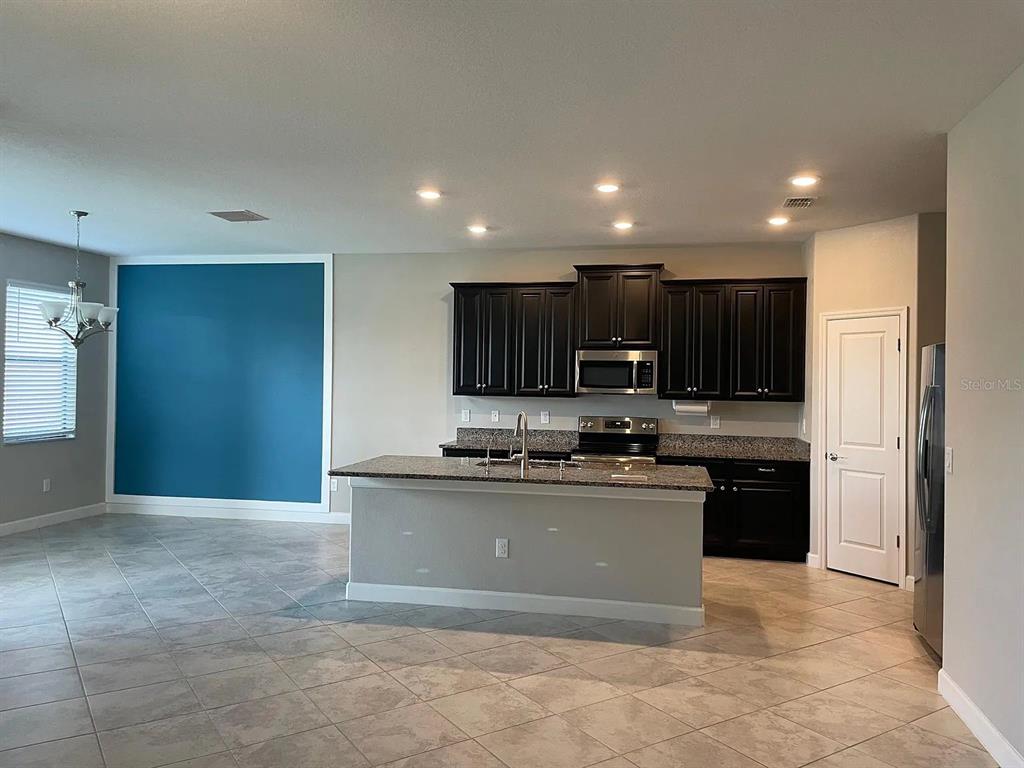A kitchen with dark cabinets, granite countertops, a center island, and a blue accent wall — 9671 IVORY DRIVE, SUN CITY CENTER, FL