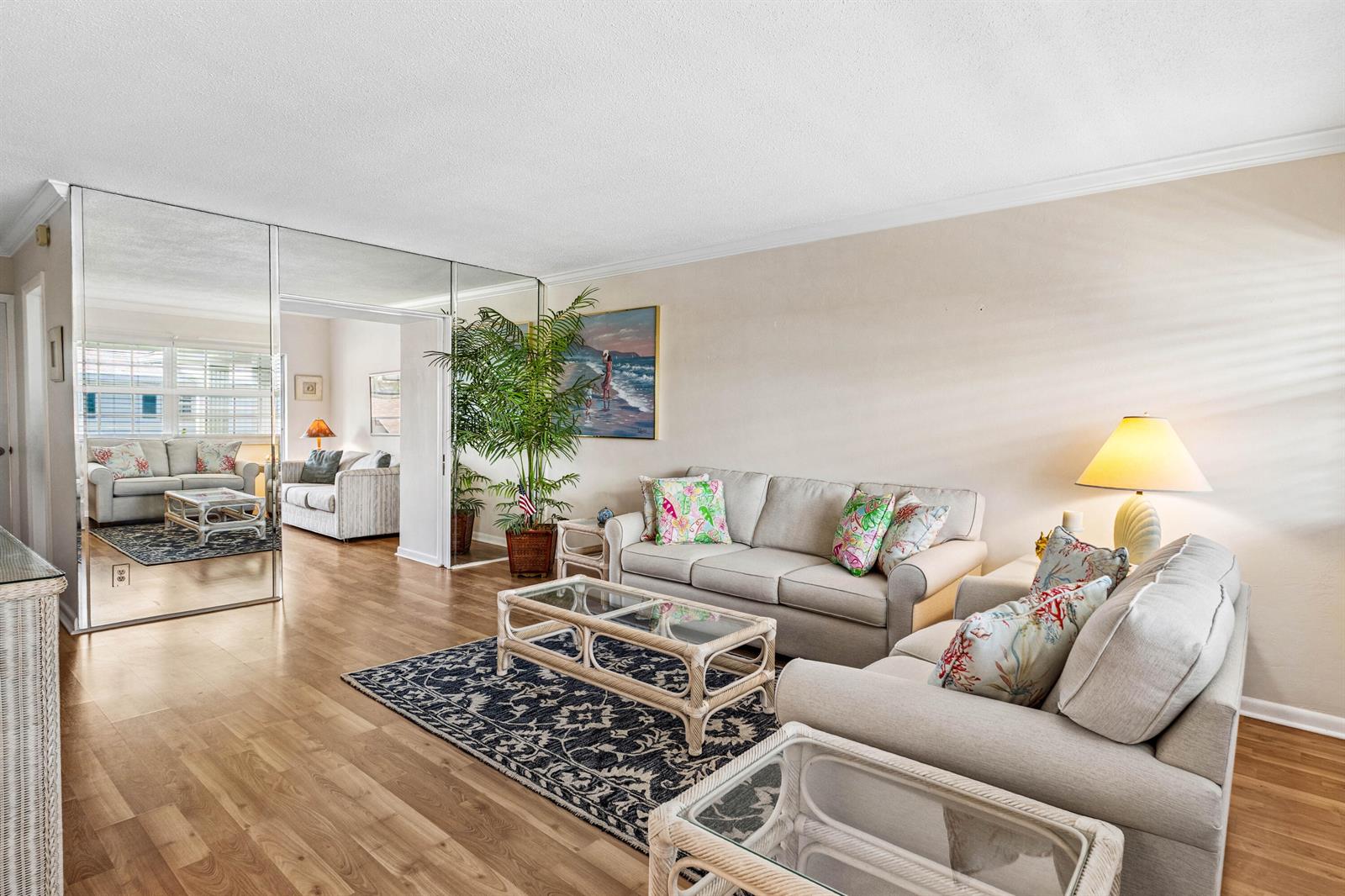 A living room features light-colored sofas, a glass-topped rattan coffee table, and mirrored wall panels — 5505 N Ocean Boulevard # 204, Ocean Ridge FL 33435, OCEAN RIDGE, FL