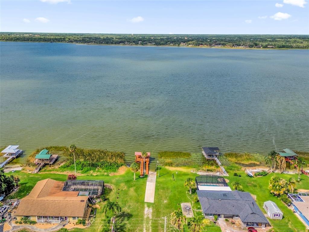 An aerial view shows two waterfront houses with private docks on a large lake — 5202 SYDNEY ROAD, FRUITLAND PARK, FL