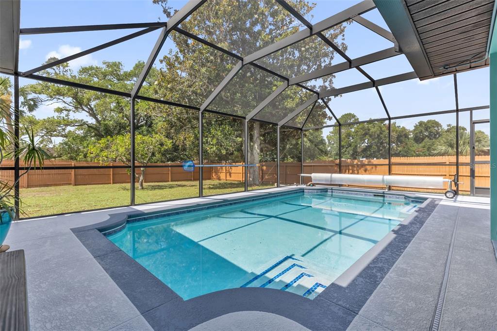 A screened-in swimming pool with a concrete deck and a wooden fence in the backyard — 5202 SYDNEY ROAD, FRUITLAND PARK, FL
