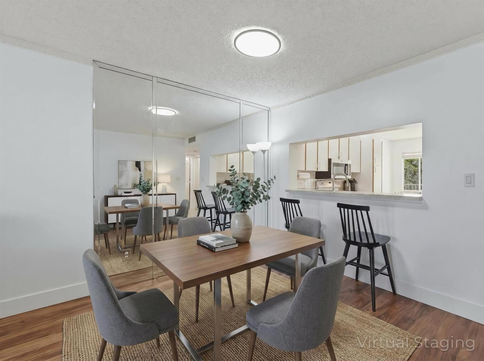 A dining room with a wooden table, gray chairs, and a large mirrored wall — 7292 S Devon Drive # 302, Tamarac FL 33321, TAMARAC, FL