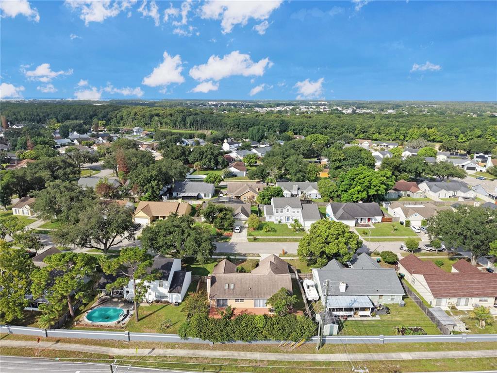 An aerial view shows a suburban neighborhood with houses, green trees, and a swimming pool — 4645 SADDLE CREEK PLACE, ORLANDO, FL