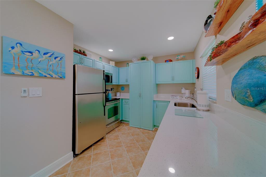 A kitchen features light blue cabinets, stainless steel appliances, and white countertops — 13125 WILCOX ROAD UNIT 16105, LARGO, FL