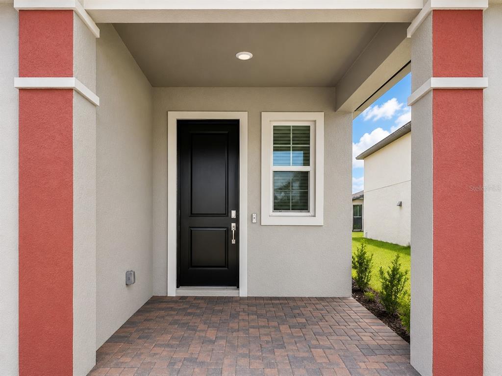 A covered entryway features a black front door, a single window, and brick paver flooring — 11757 71ST AVENUE E, PALMETTO, FL