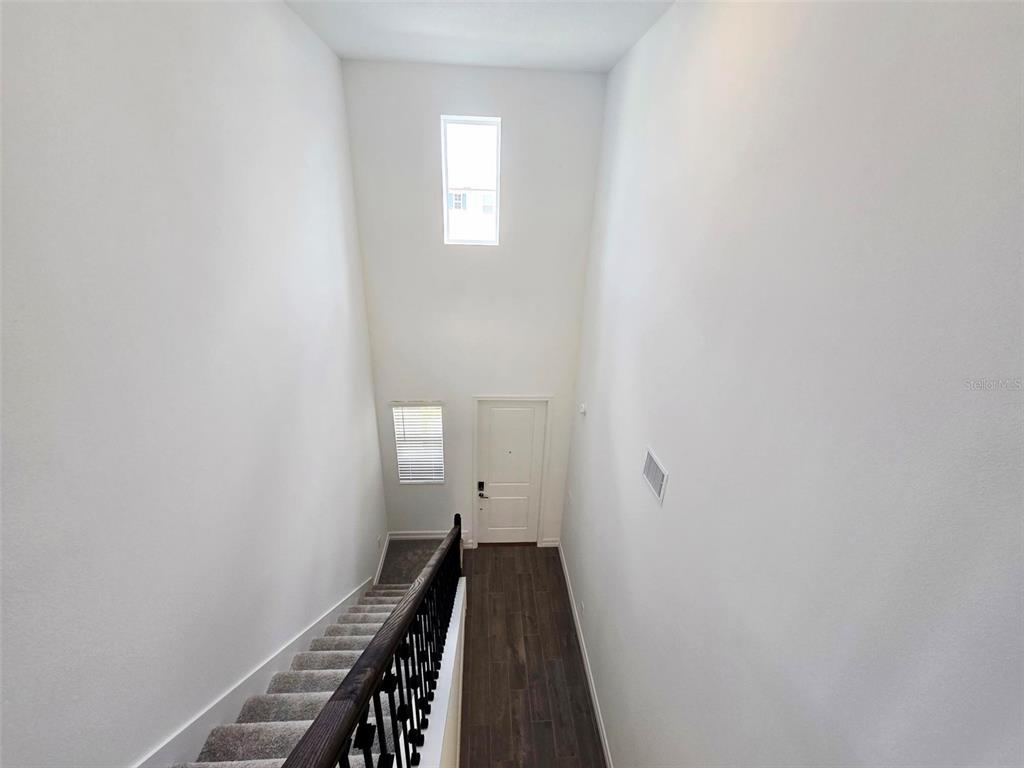 A high-ceilinged entryway features a staircase with carpeted steps and a dark wood railing — 11757 71ST AVENUE E, PALMETTO, FL