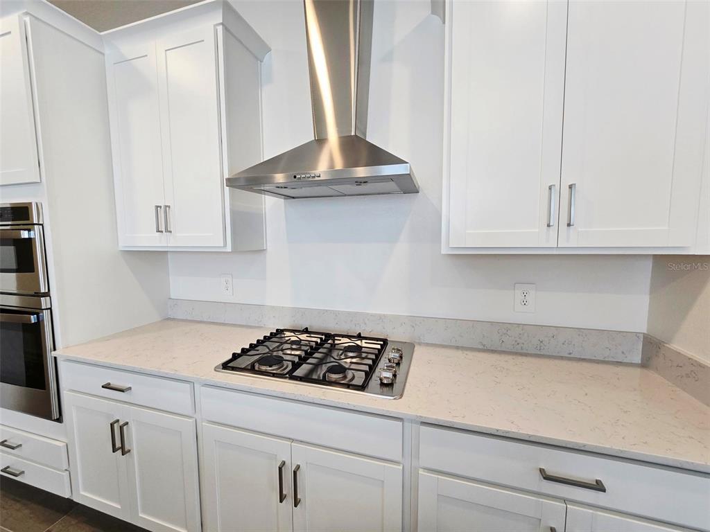 A kitchen features white cabinets, a stainless steel range hood, and a gas cooktop — 11757 71ST AVENUE E, PALMETTO, FL