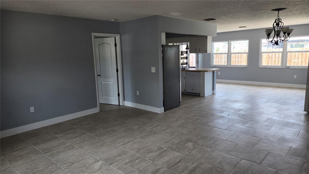 An open-concept living area with gray walls, tile flooring, and a view into the kitchen — 347 HOLLY ROAD, VENICE, FL