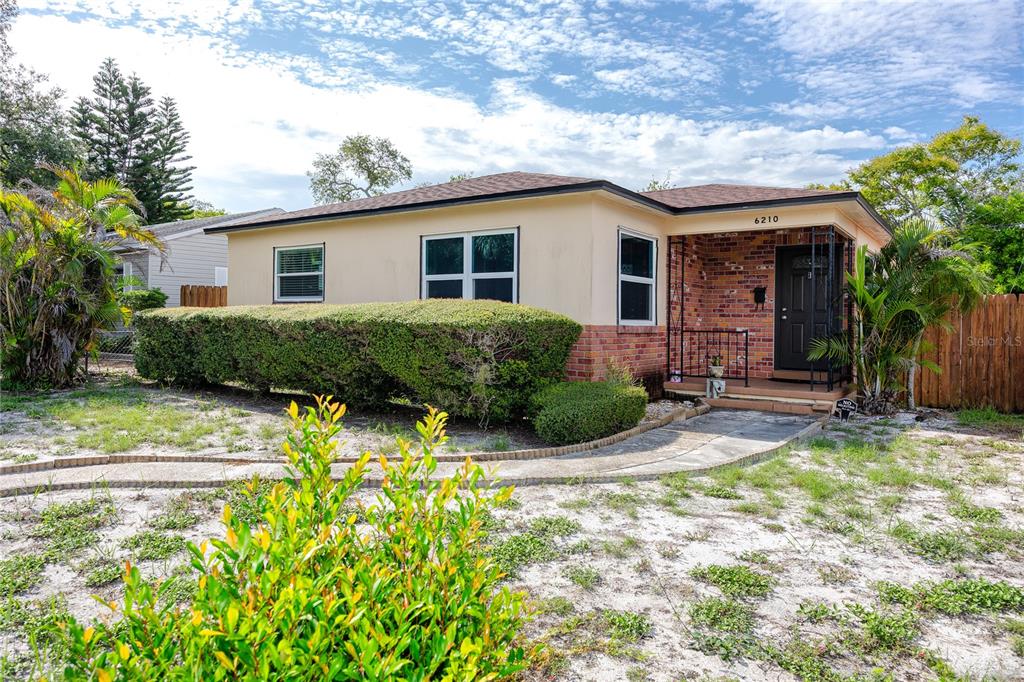 A single-story house with a brick and stucco exterior features a front porch and landscaping — 6210 4TH AVENUE S, ST PETERSBURG, FL